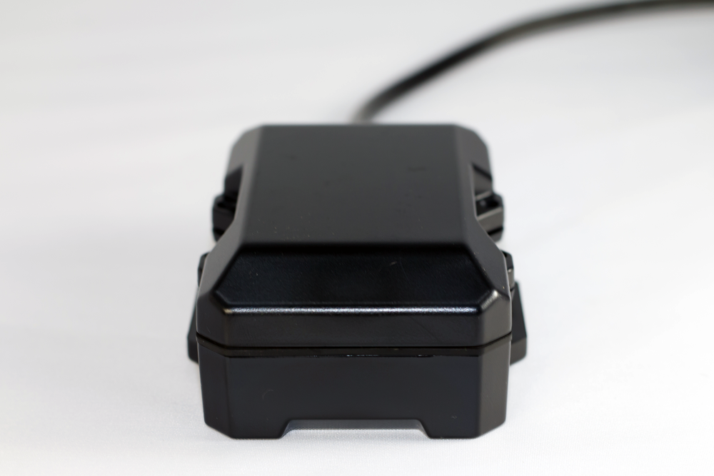 Black rectangular device with a cable, angled on a white surface.