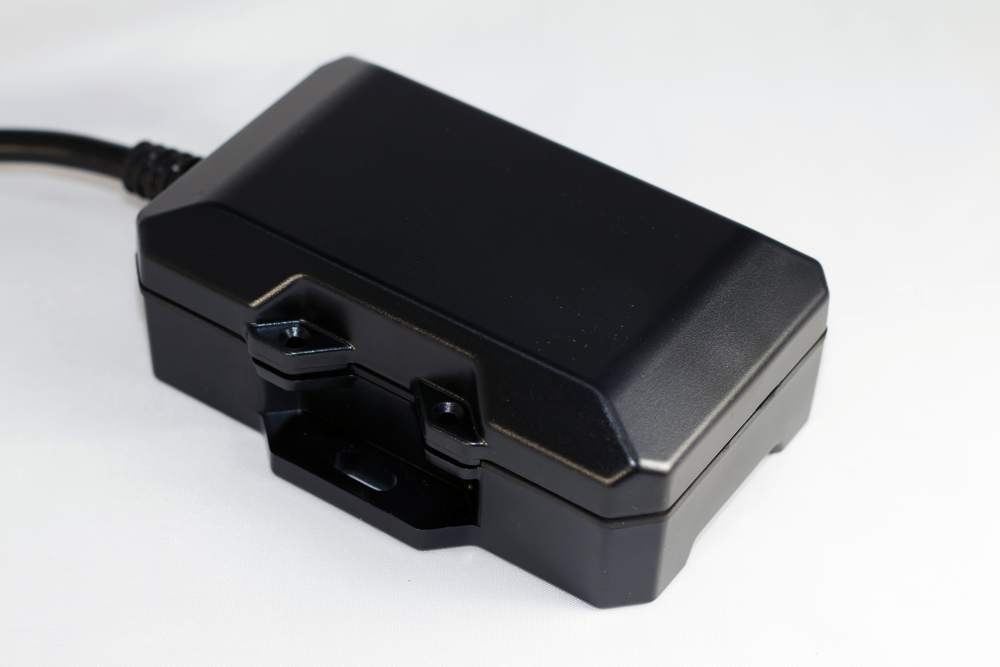 Black electronic device with a mounting bracket and attached cable.