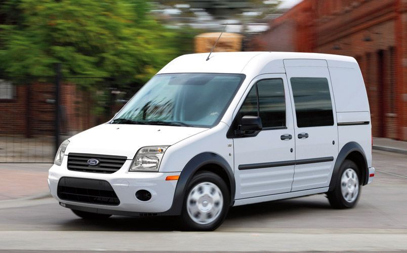 White Ford Transit Connect van driving on a street.