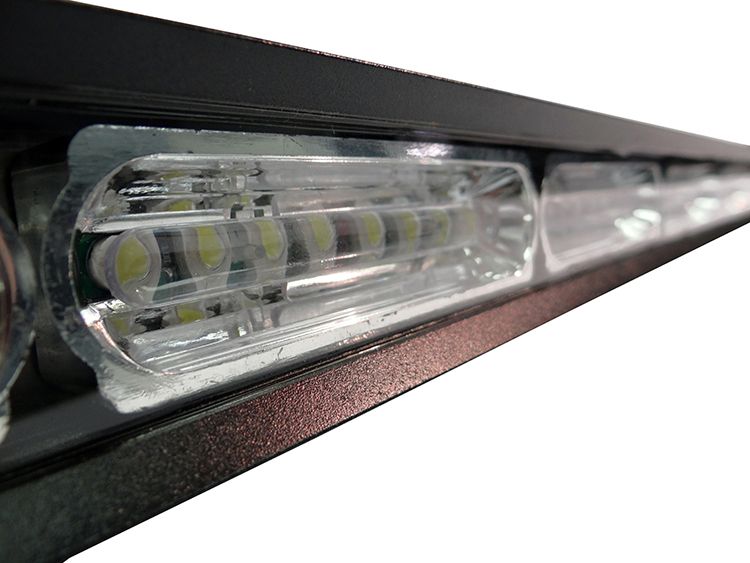 Close-up of a black emergency light bar with clear lenses and bright white LED lights.