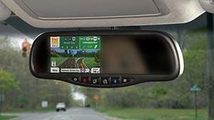 Rearview mirror displaying navigation directions. Road and trees visible in background.