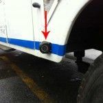 Red arrow points to a small black camera mounted on a white vehicle with blue trim.