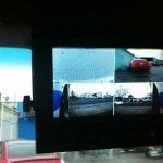View from a vehicle with split screens: sky, rain, red car, and side views.