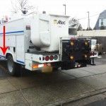 Utility truck with white body and lift, parked on concrete, arrow pointing at side.