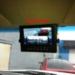 Dashboard view of a monitor displaying multiple camera views, likely for a vehicle's surroundings; red car visible.