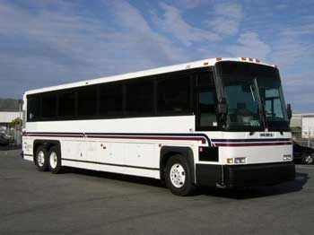 White passenger bus with tinted windows, parked on pavement.