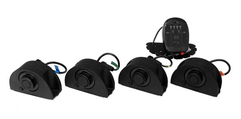 Four black proximity sensors with a remote control on white background.