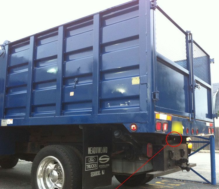 Blue dump truck rear, parked outdoors, with visible taillights and a tow hitch.