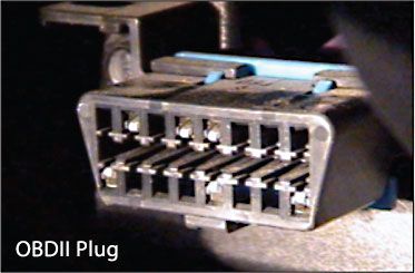 OBDII plug, black with 16 pin slots, mounted in a vehicle.