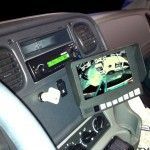 Dashboard with a screen showing a blurry truck backing up. Radio and various controls visible.