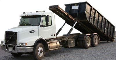 White semi-truck with black dumpster lifted in the air.