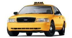 Yellow taxi cab with black grill and hubcaps, taxi light on roof.