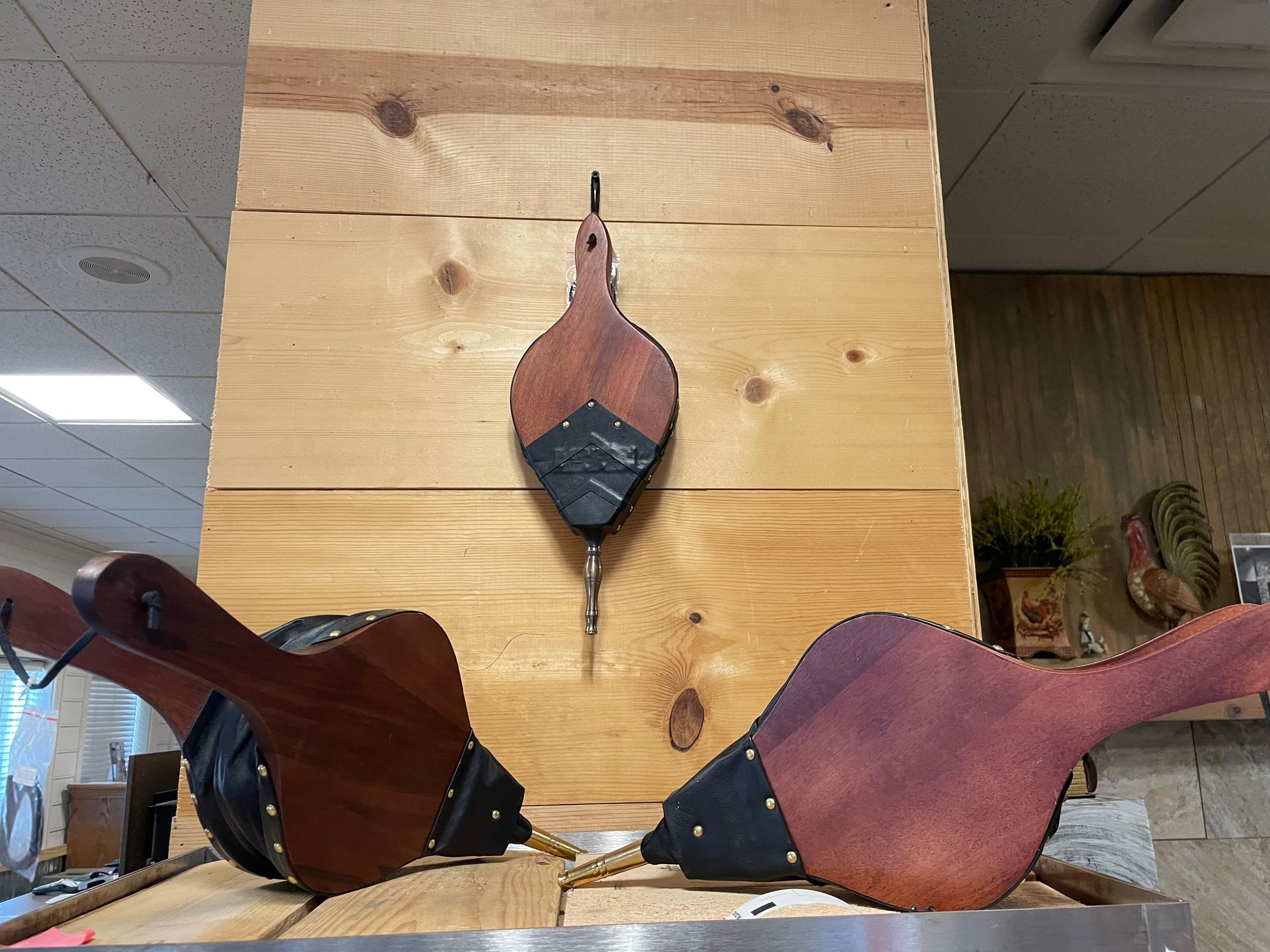 Three wooden bellows are sitting on a wooden table.