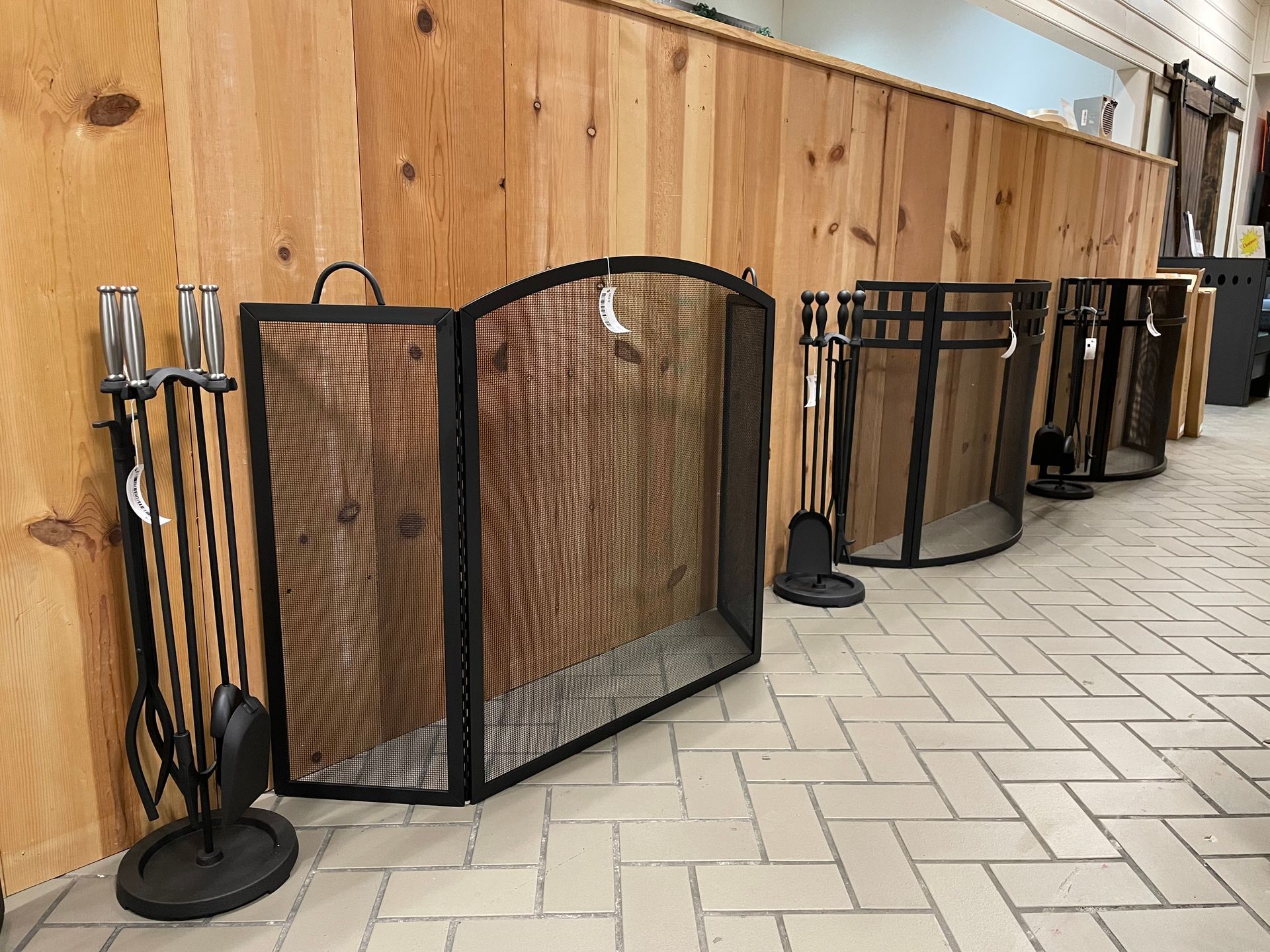 A fireplace screen is sitting on a tiled floor next to a wooden wall.