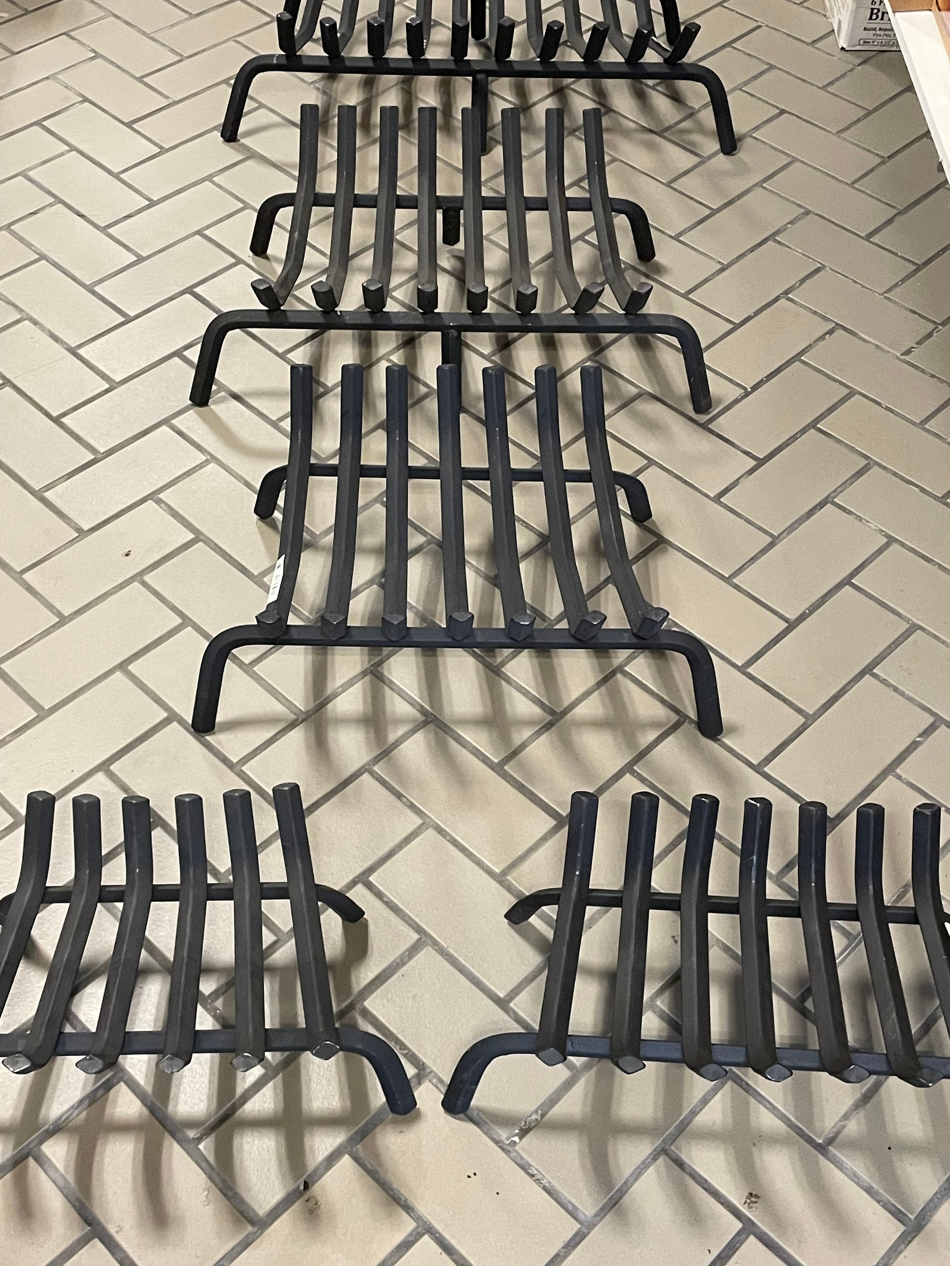 A row of fireplace grates on a brick floor