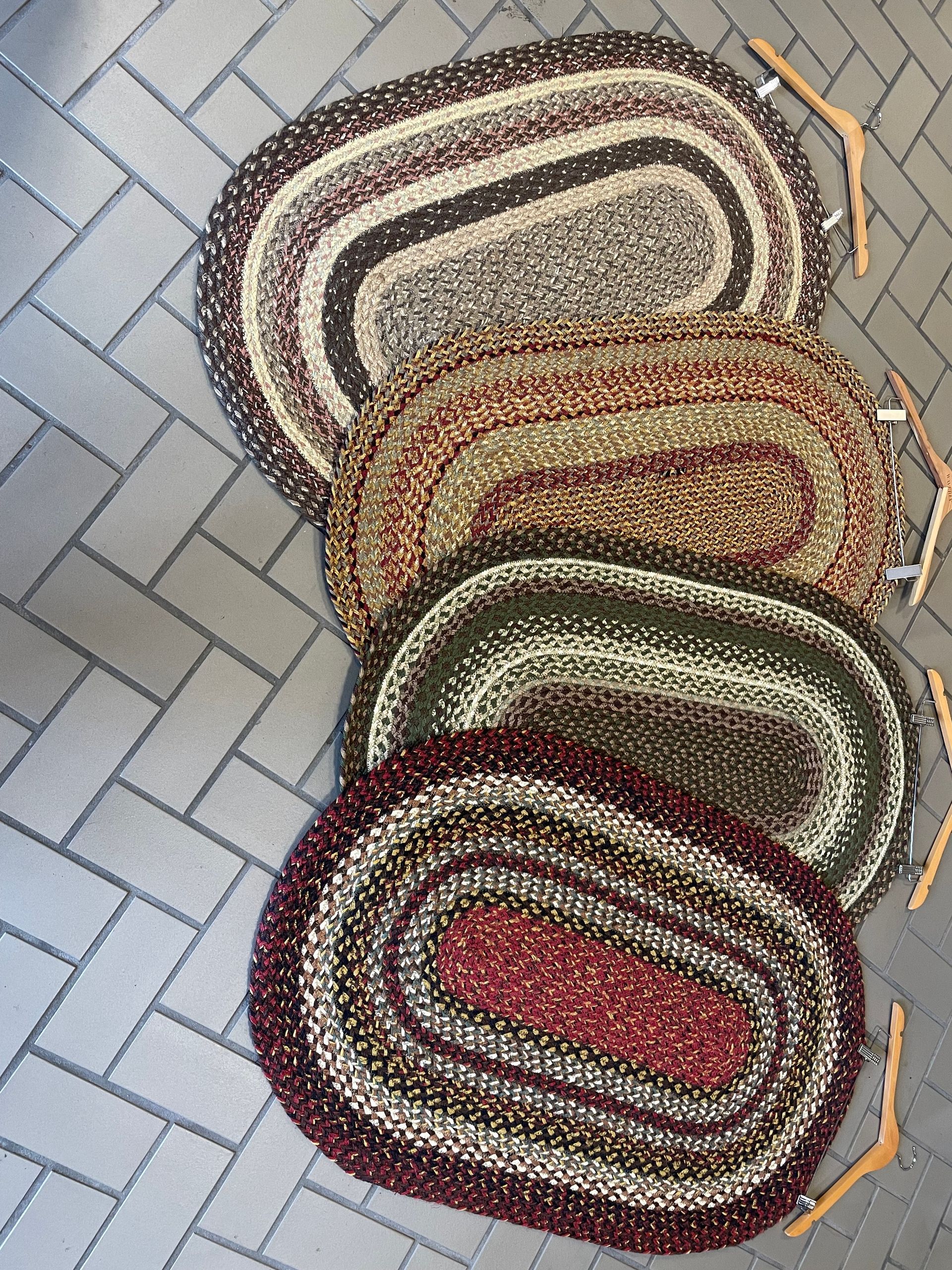 A group of rugs are stacked on top of each other on a brick floor.