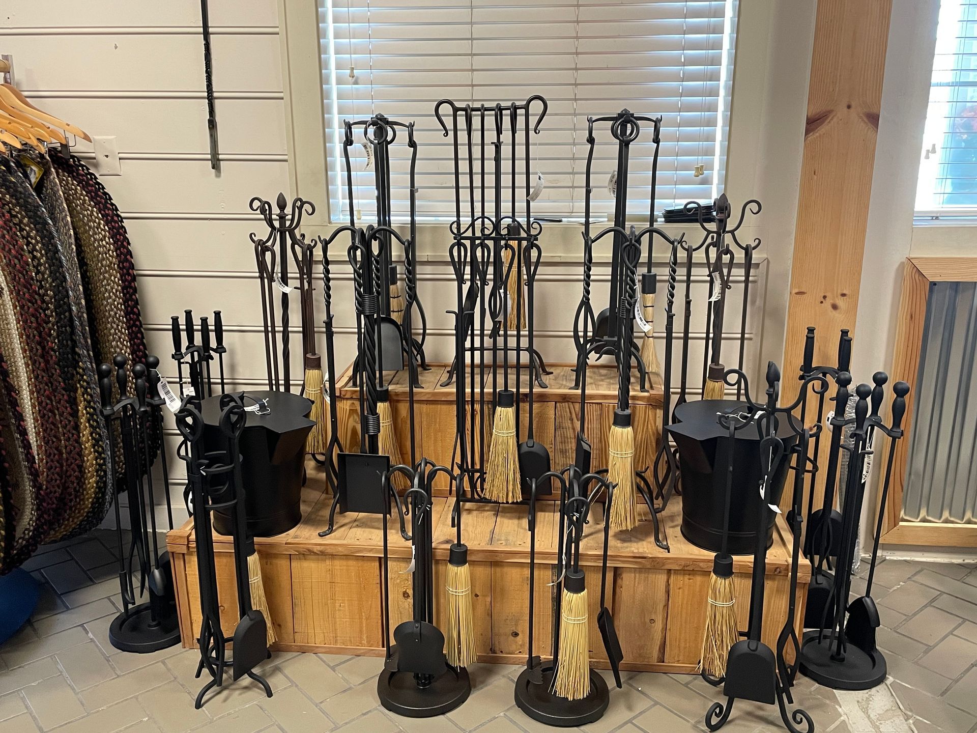 A bunch of fireplace tools are sitting on a wooden shelf in a room.