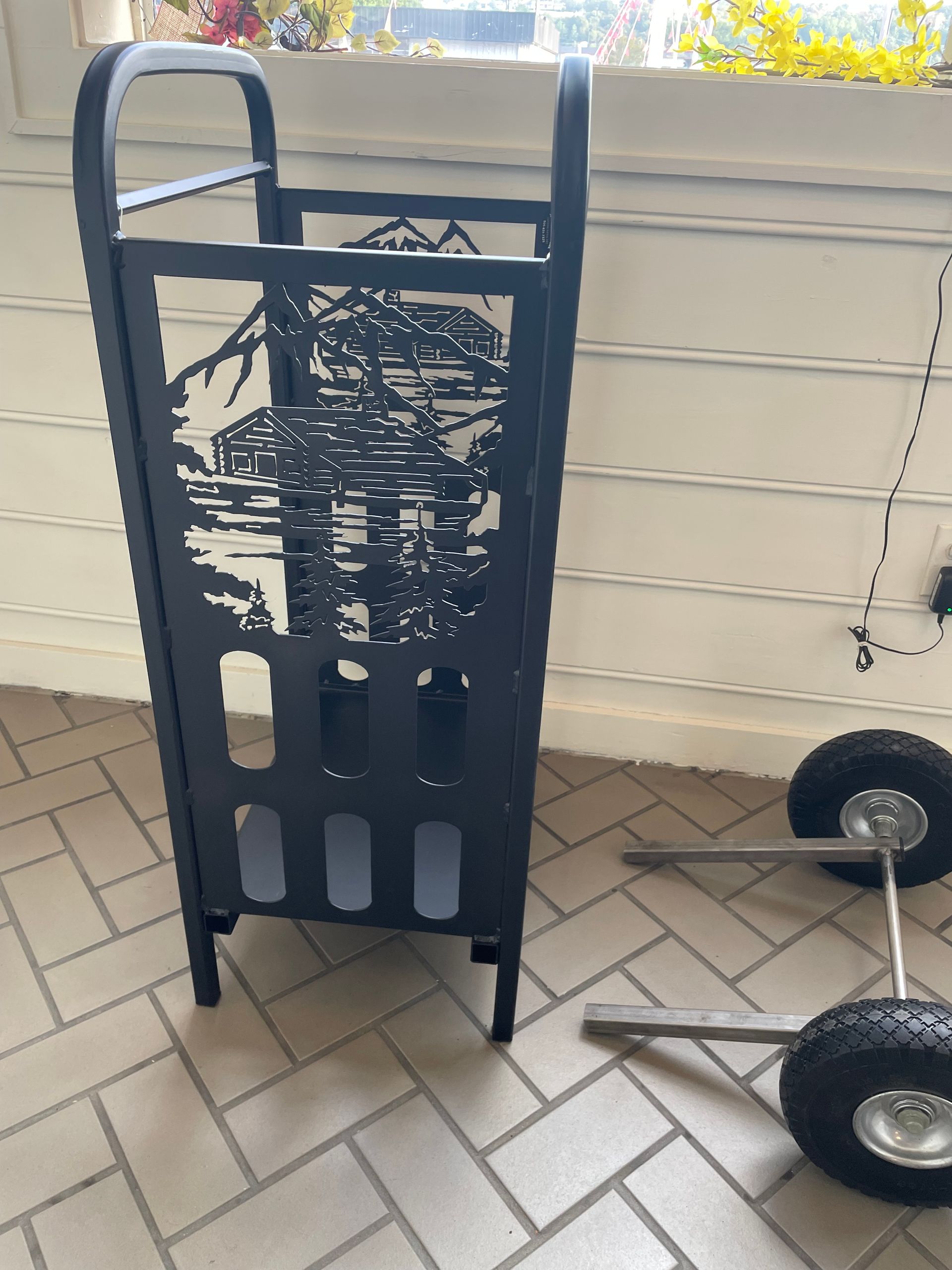 A black cart is sitting on a tiled floor next to a wheelbarrow.