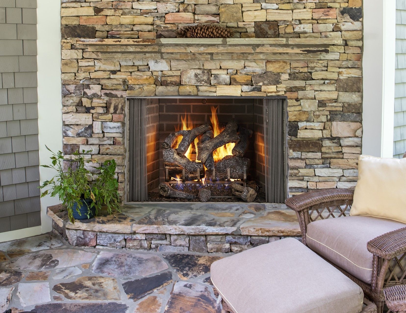 A stone fireplace with a chair and ottoman in front of it