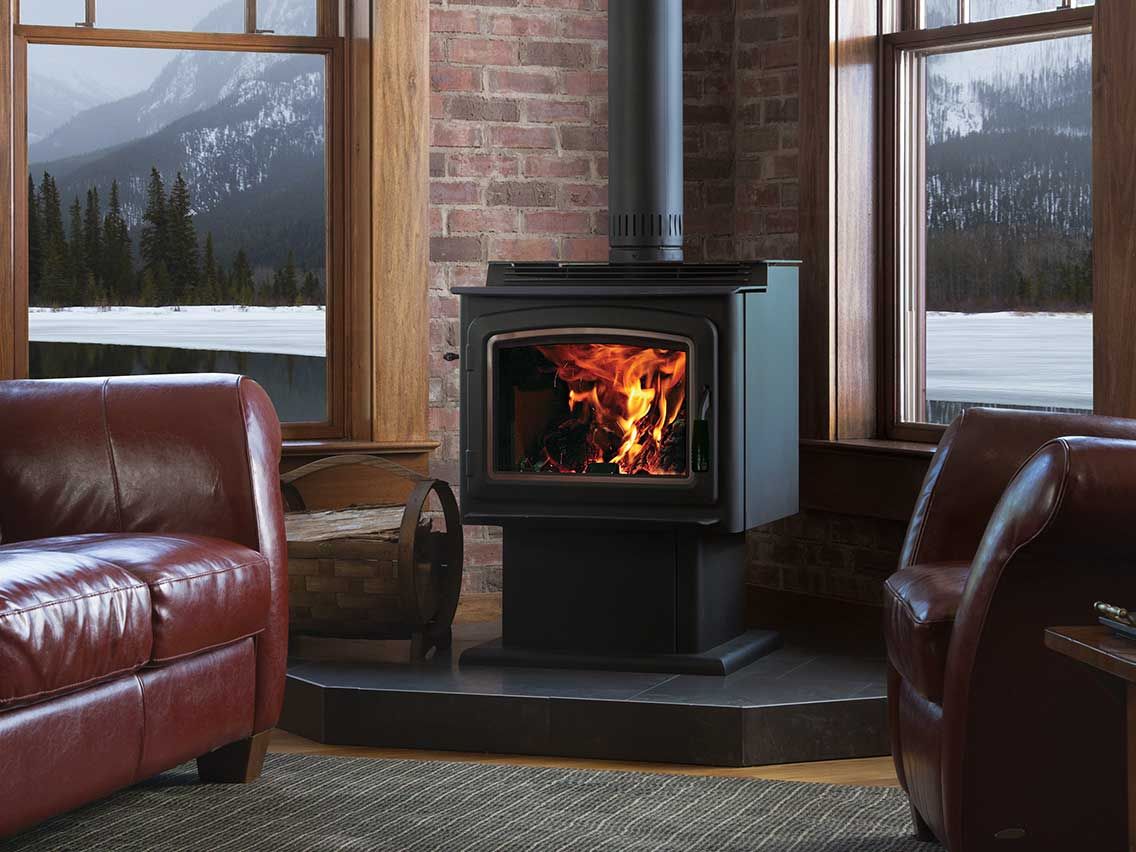 A wood stove is sitting in a living room next to a couch and chairs.