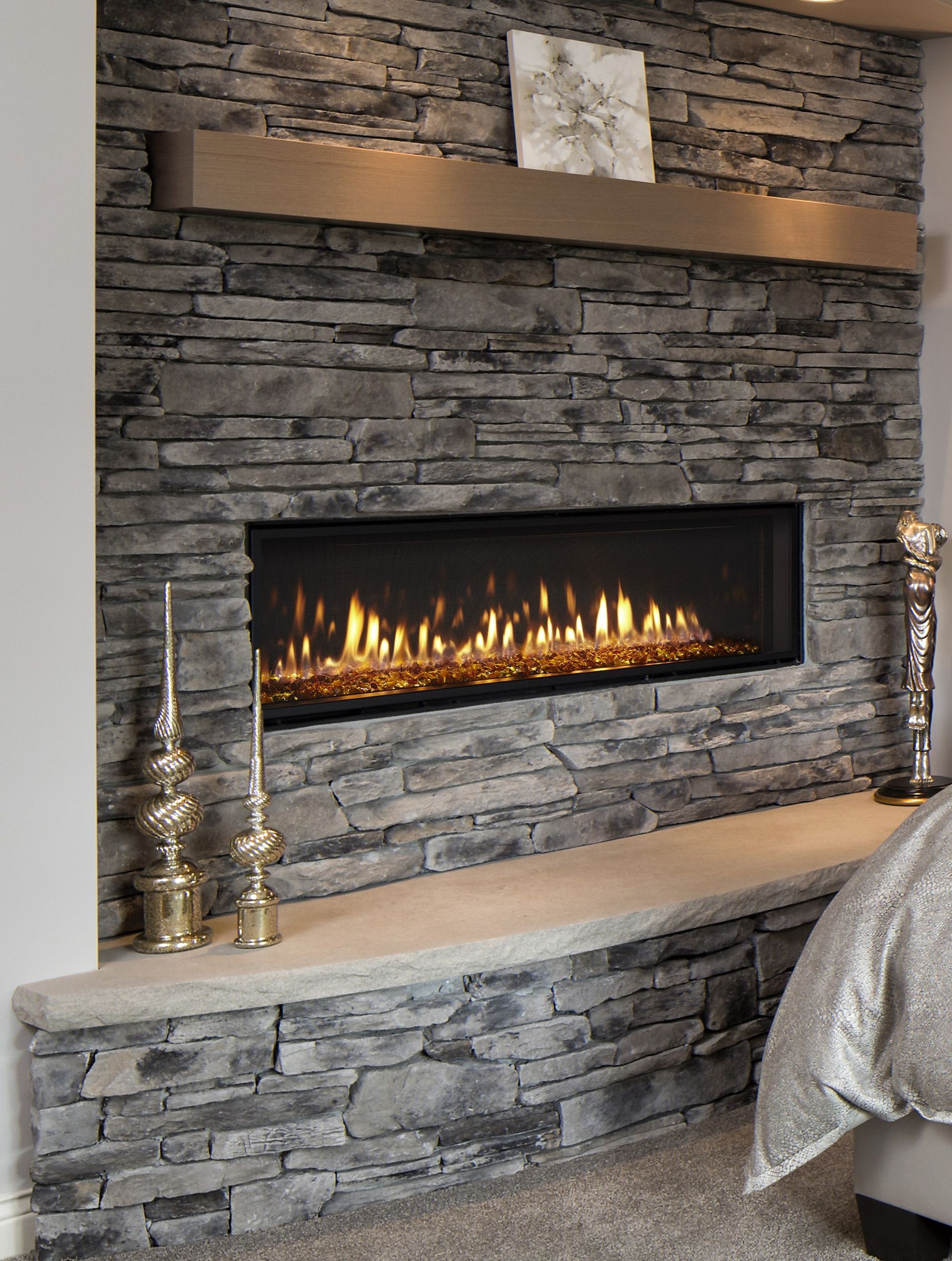 A fireplace is built into a stone wall in a bedroom.