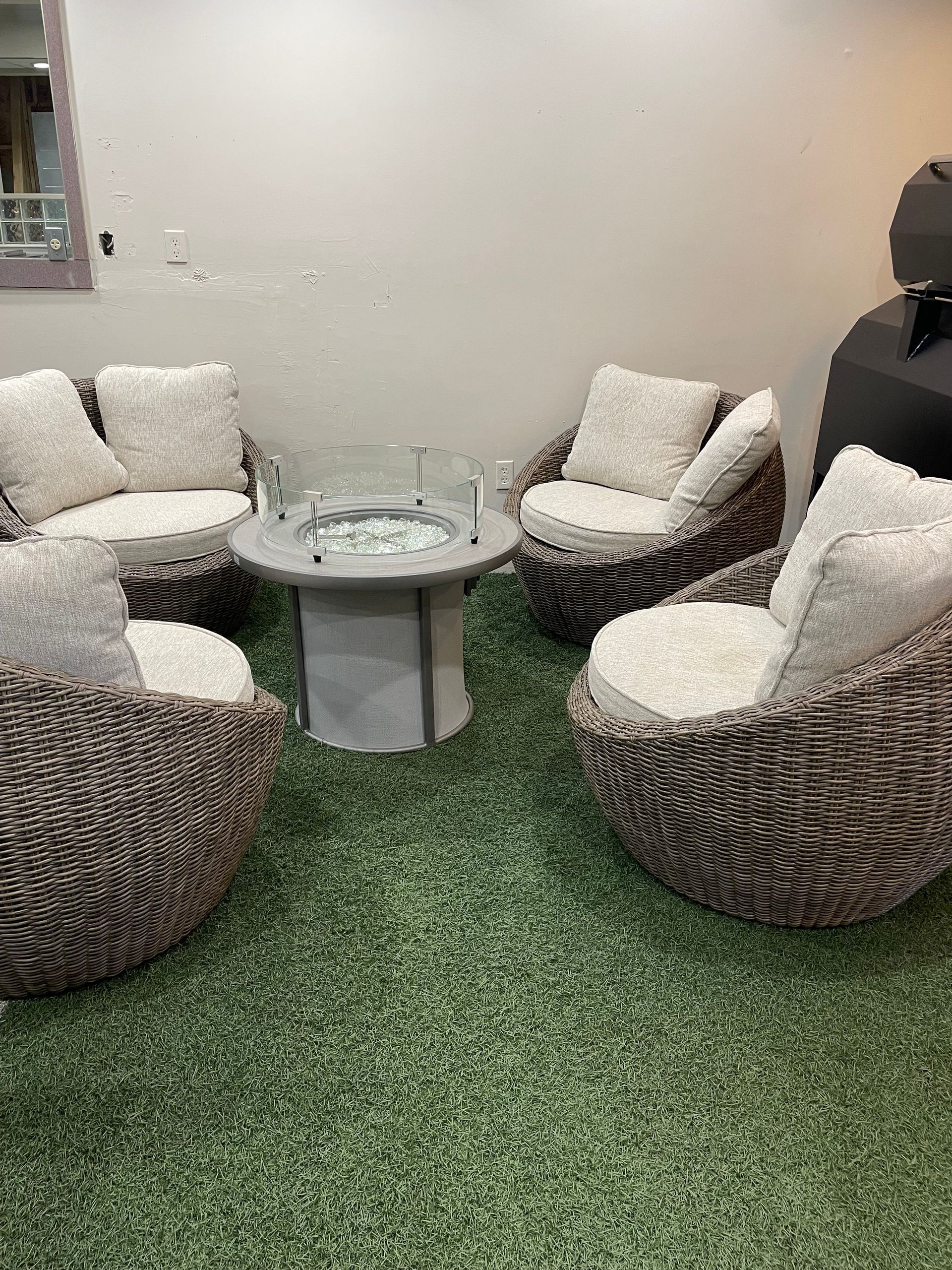A living room with wicker furniture and a fire pit.