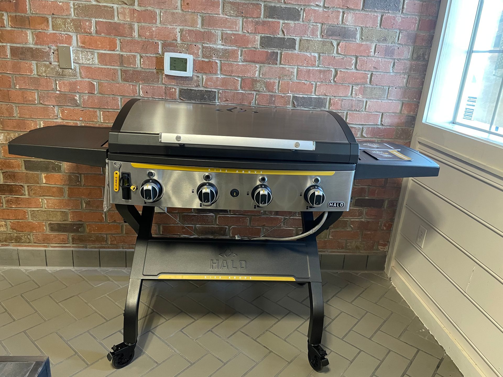 A grill is sitting in front of a brick wall.