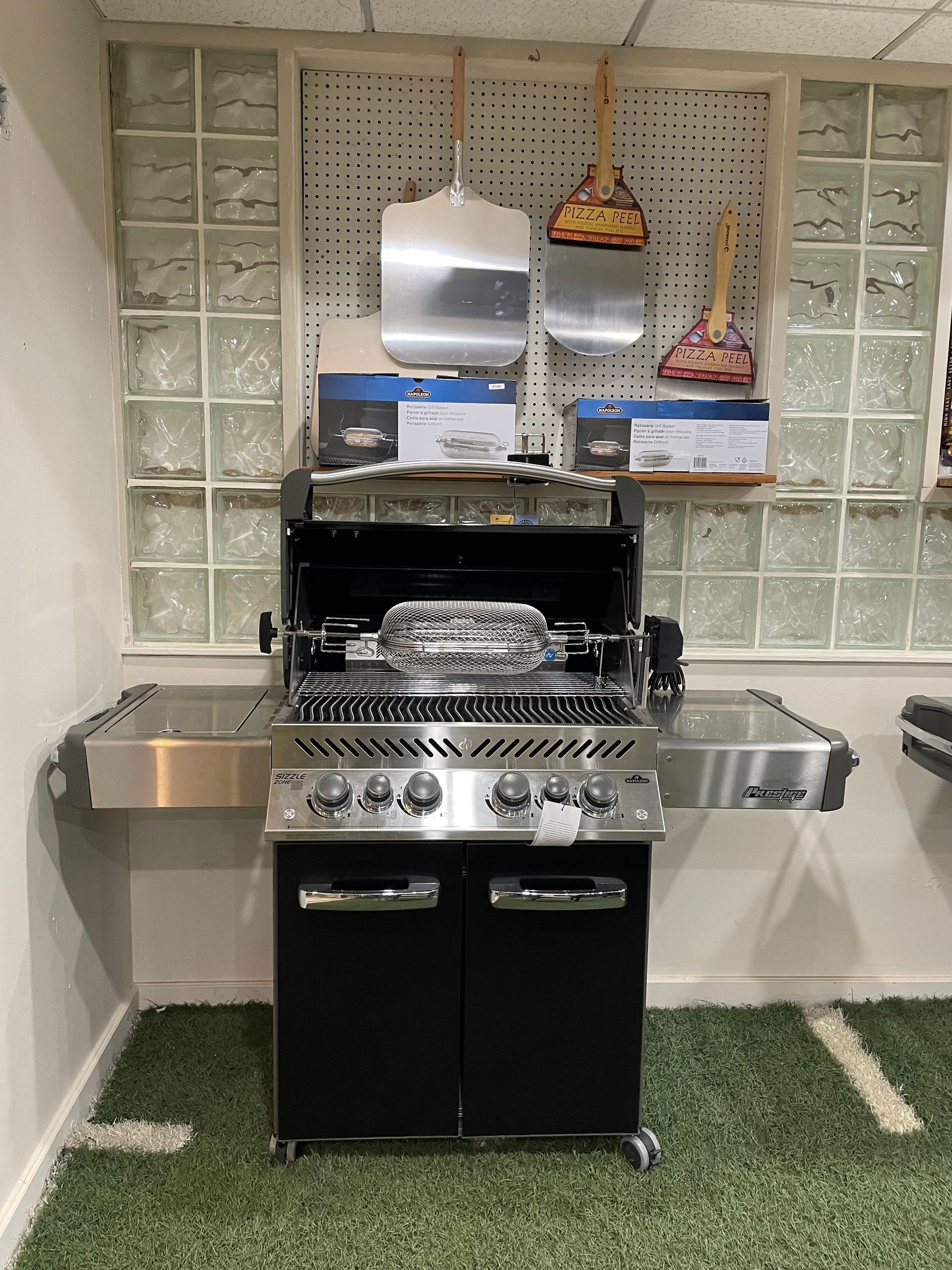 A stainless steel grill is sitting on top of a green carpet in a room.