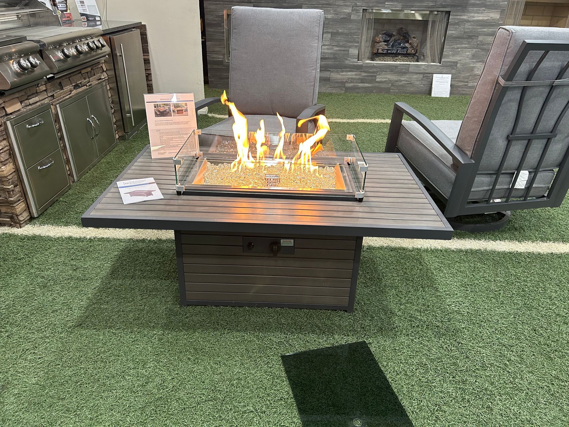 A fire pit is sitting on top of a table next to a chair.