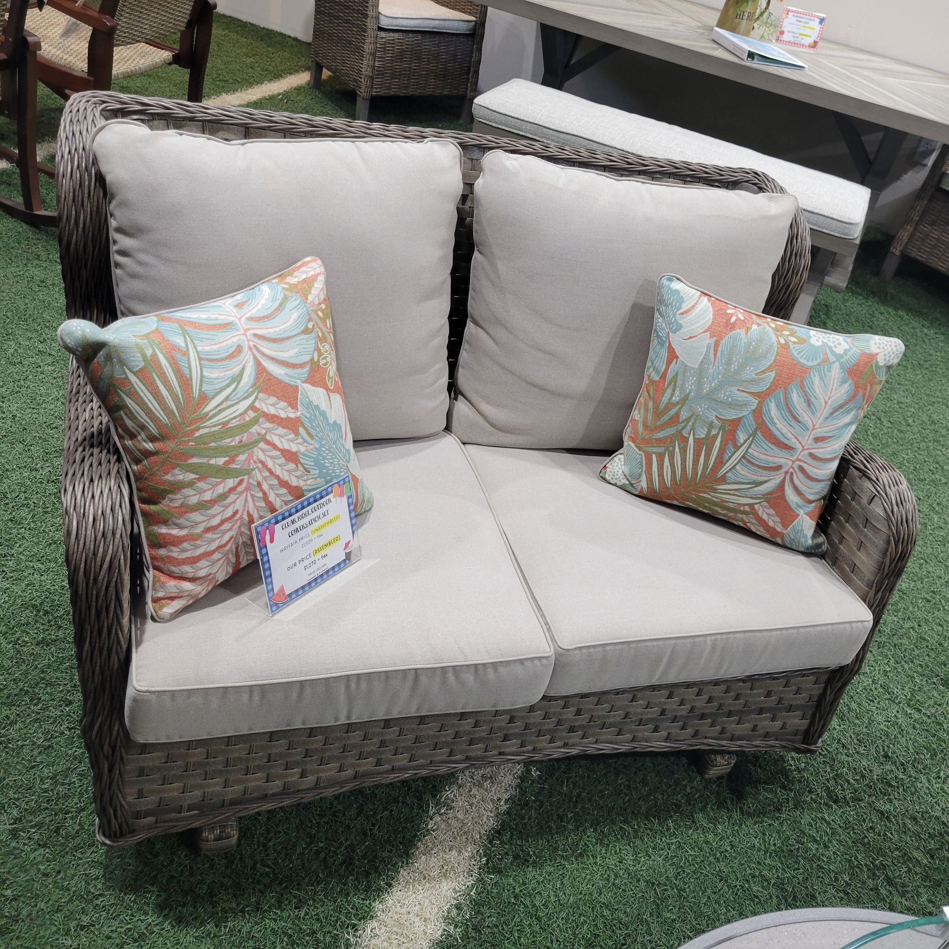 A wicker couch with two pillows on it.