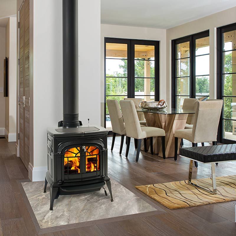 A wood stove in a living room next to a table and chairs