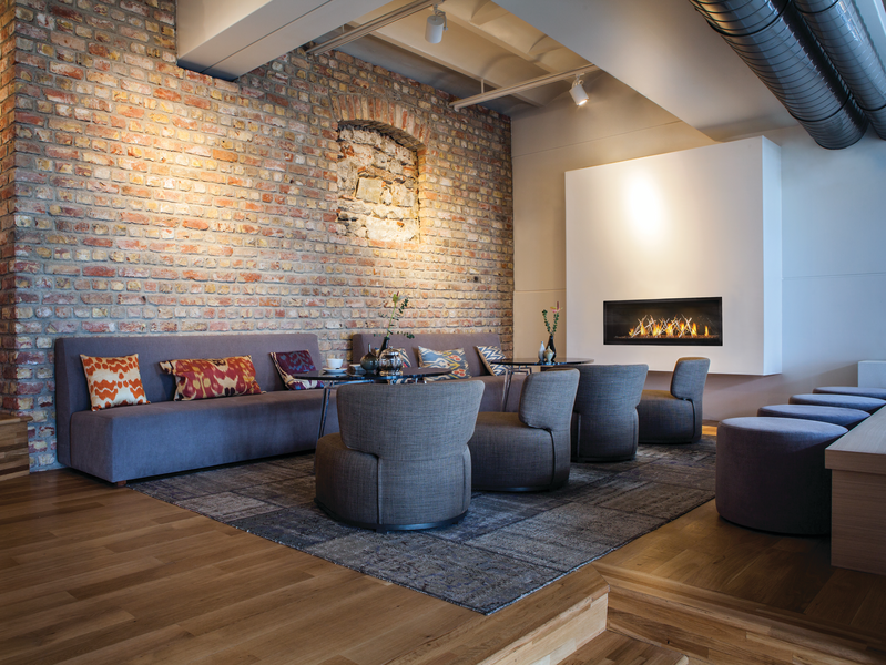 A living room with a couch, chairs, ottomans, and a fireplace.