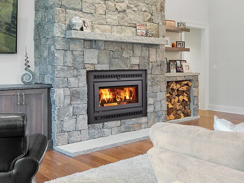 Stone fireplace with a lit fire, built-in shelves, and a cozy living room with wood flooring.