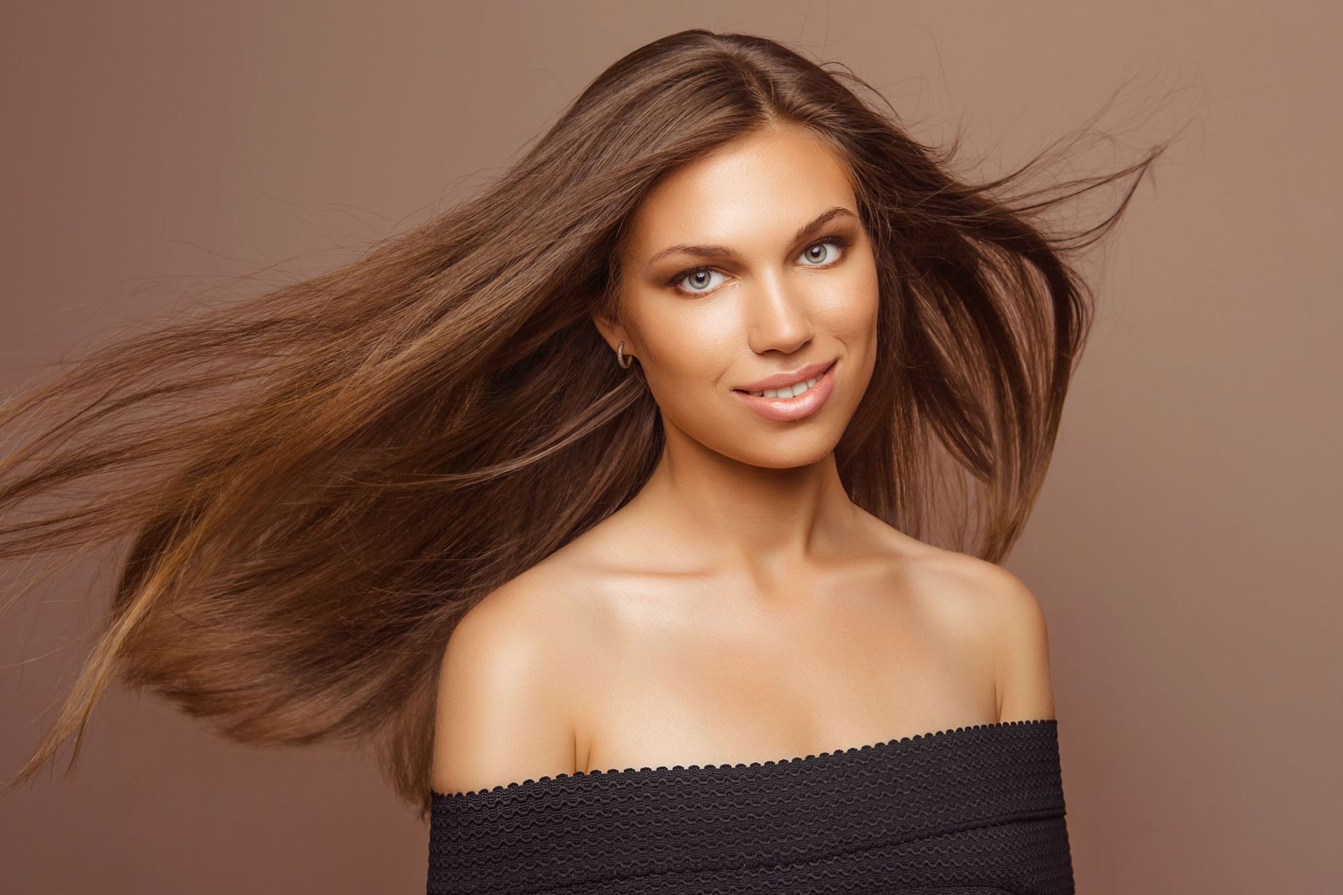 A woman smiling at the camera as her hair flies in the wind.