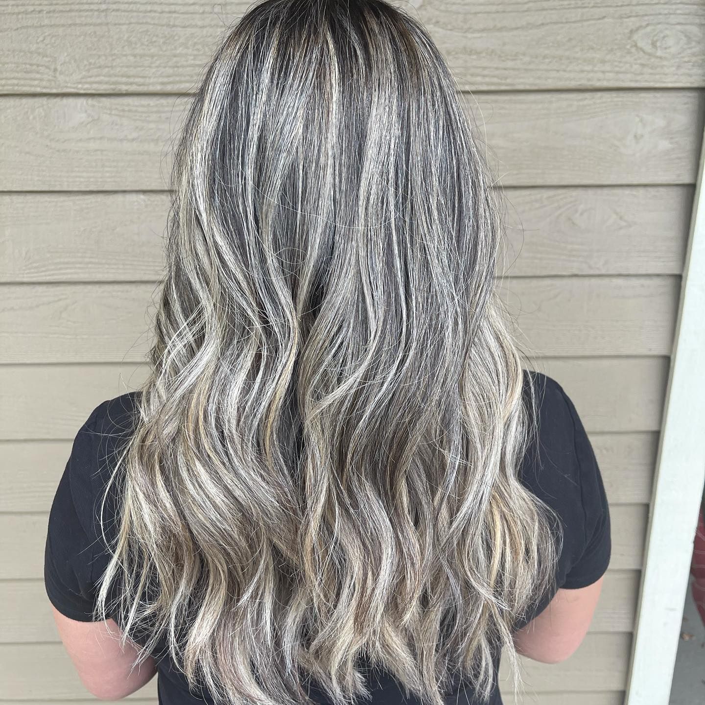 A woman with long hair is standing in front of a house.
