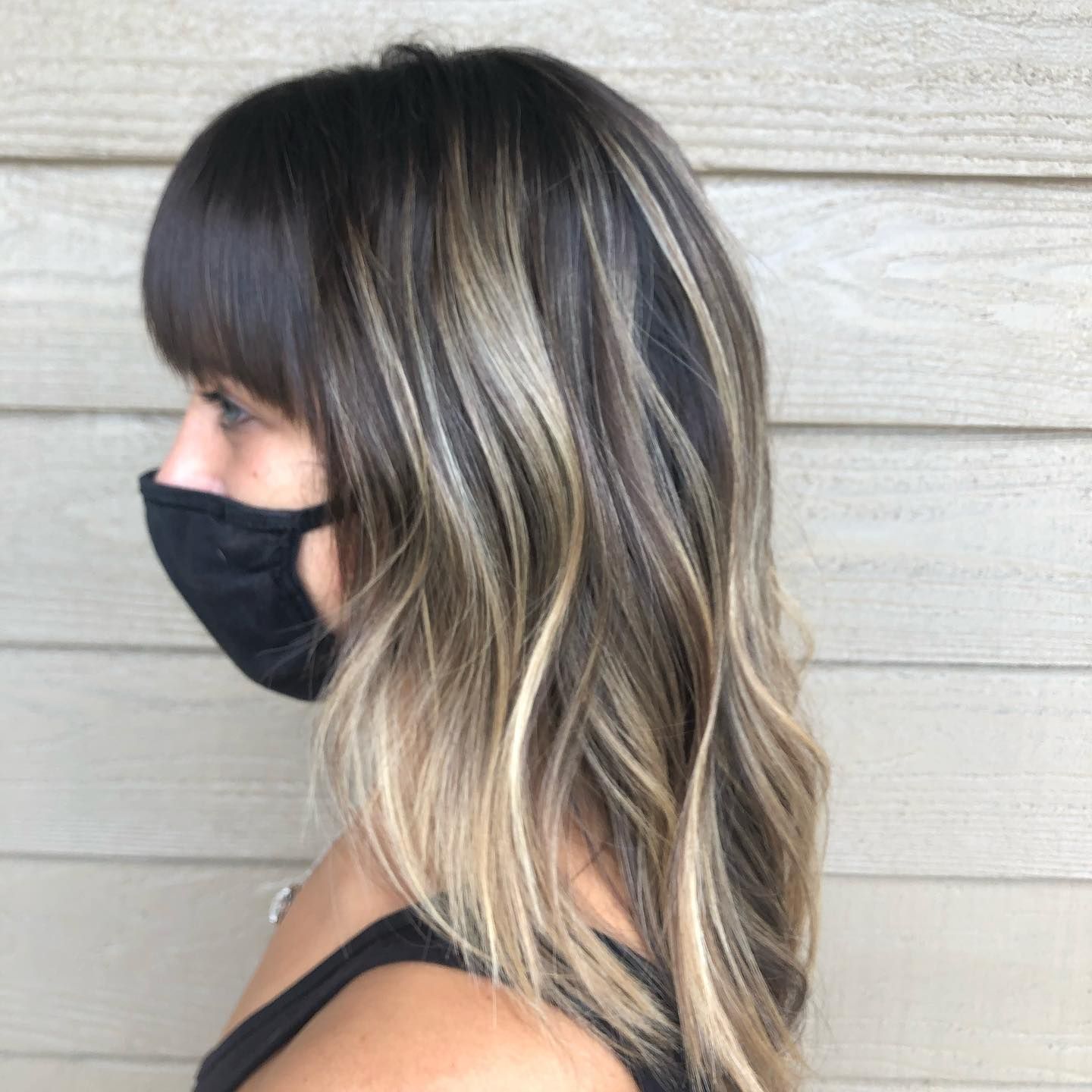 A woman wearing a black face mask has long hair