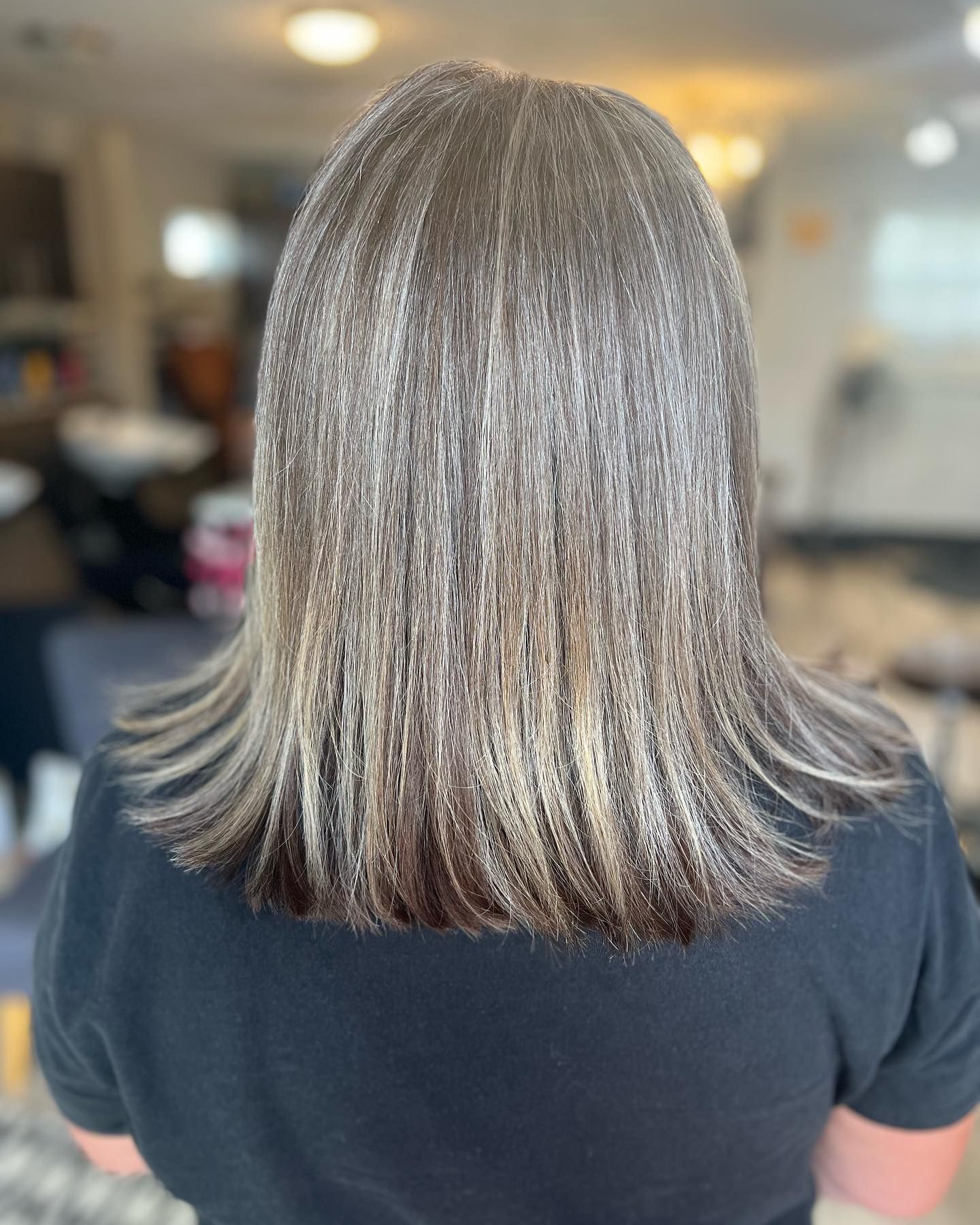 The back of a woman 's head with long hair and a black shirt.
