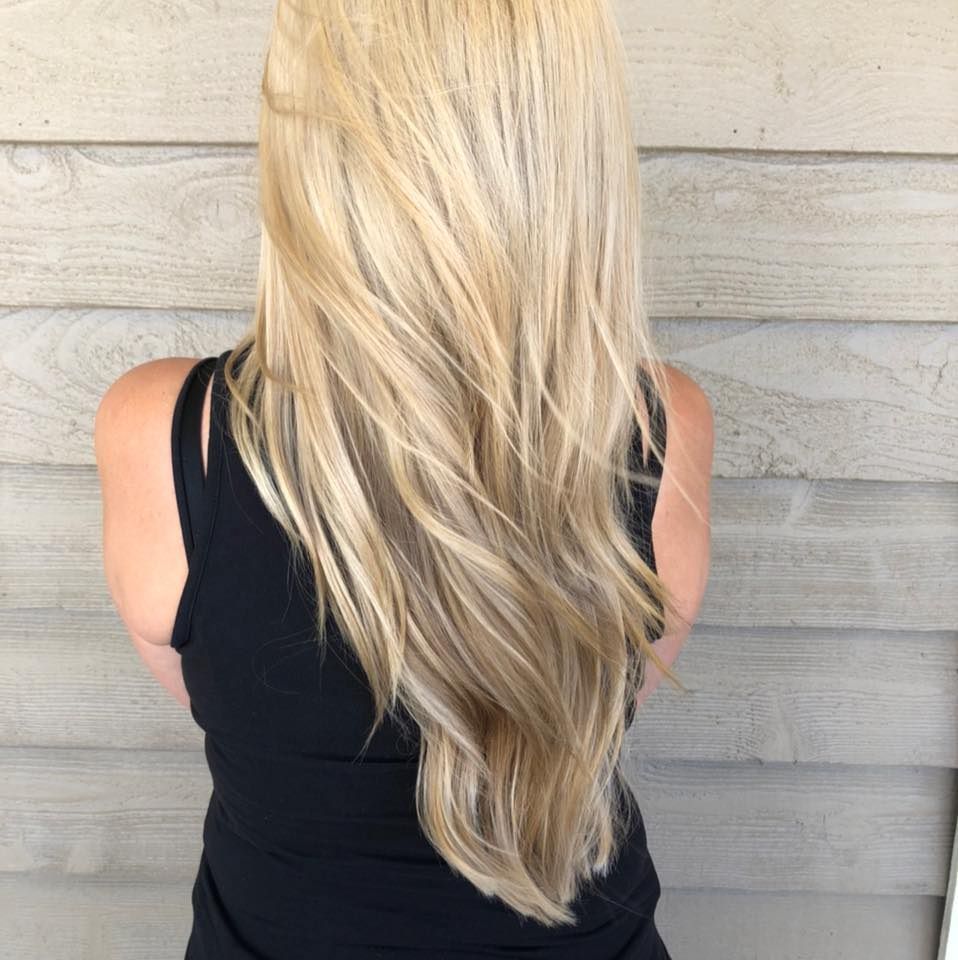 A woman with long blonde hair is wearing a black tank top