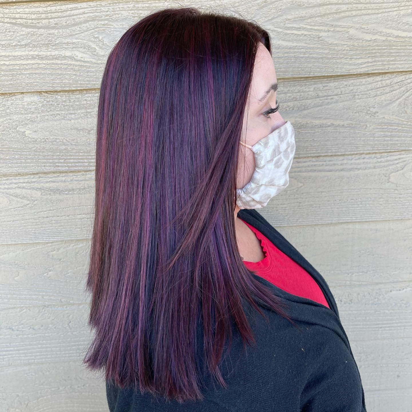 A woman with long purple hair is wearing a face mask.