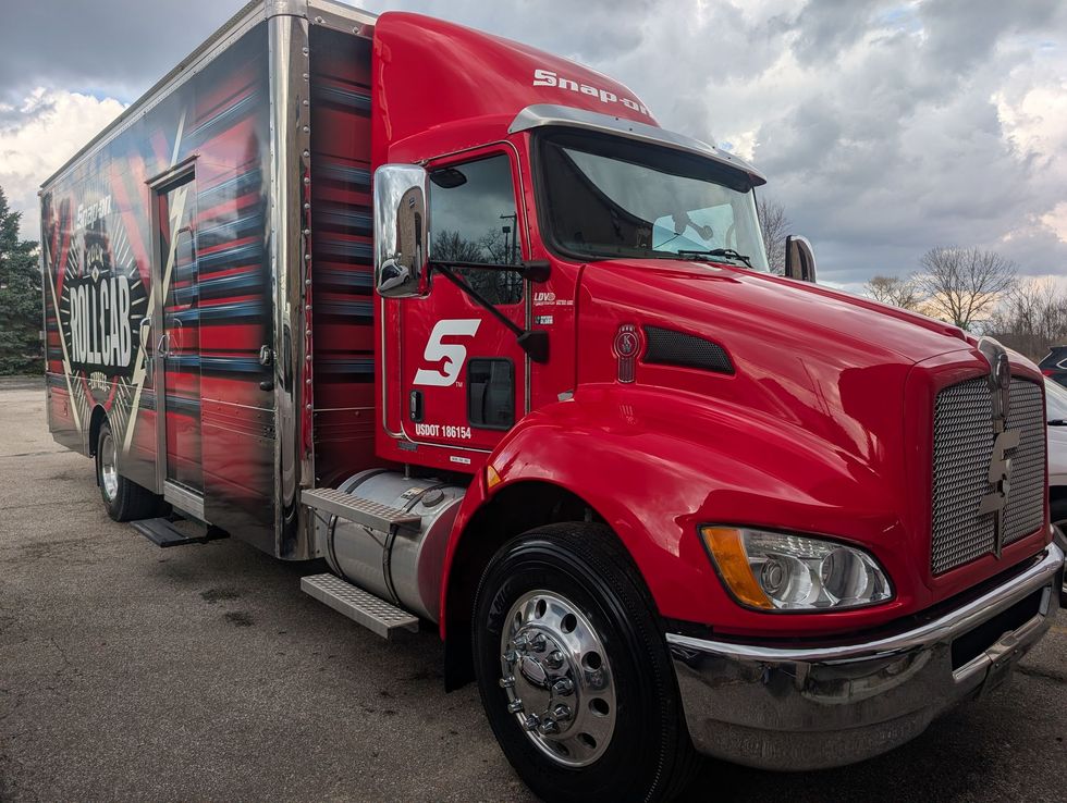Red semi-truck with a large trailer parked on a cloudy day