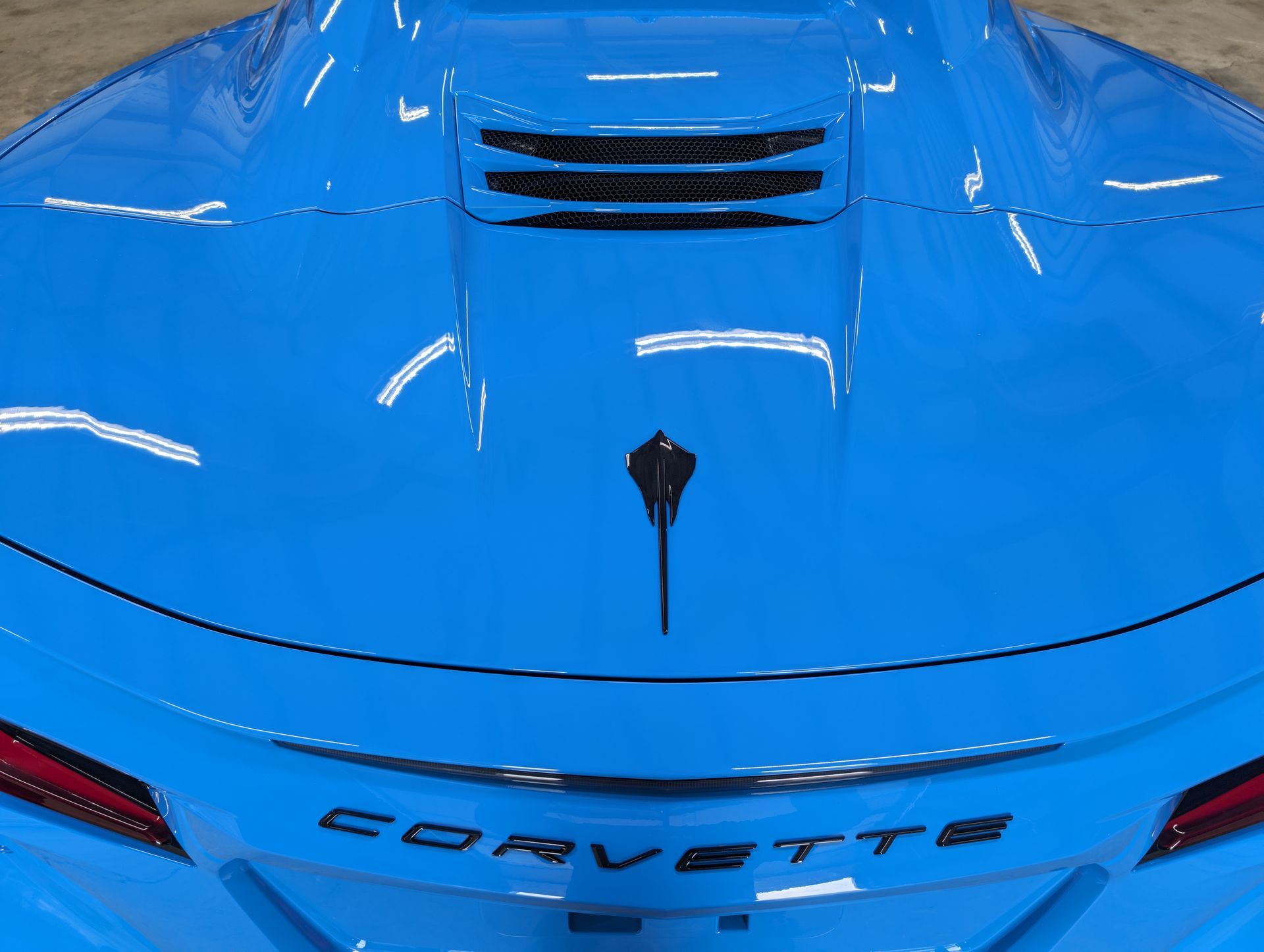 Rear view of a blue Corvette sports car with black vents and “CORVETTE” badging.