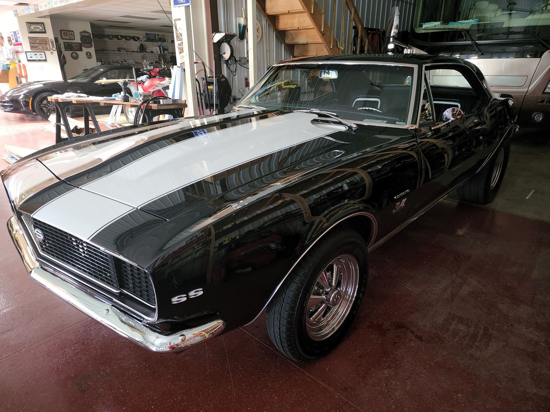 Black classic muscle car with chrome grille parked indoors in a showroom/garage.