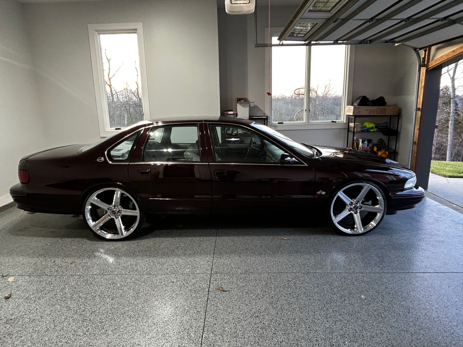 Dark maroon sedan with chrome rims parked in a garage.