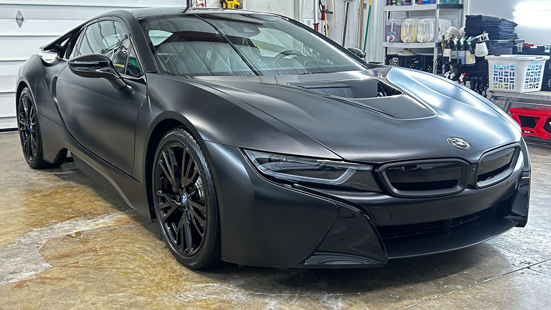 Black BMW sports coupe parked in a garage, front three-quarter view.