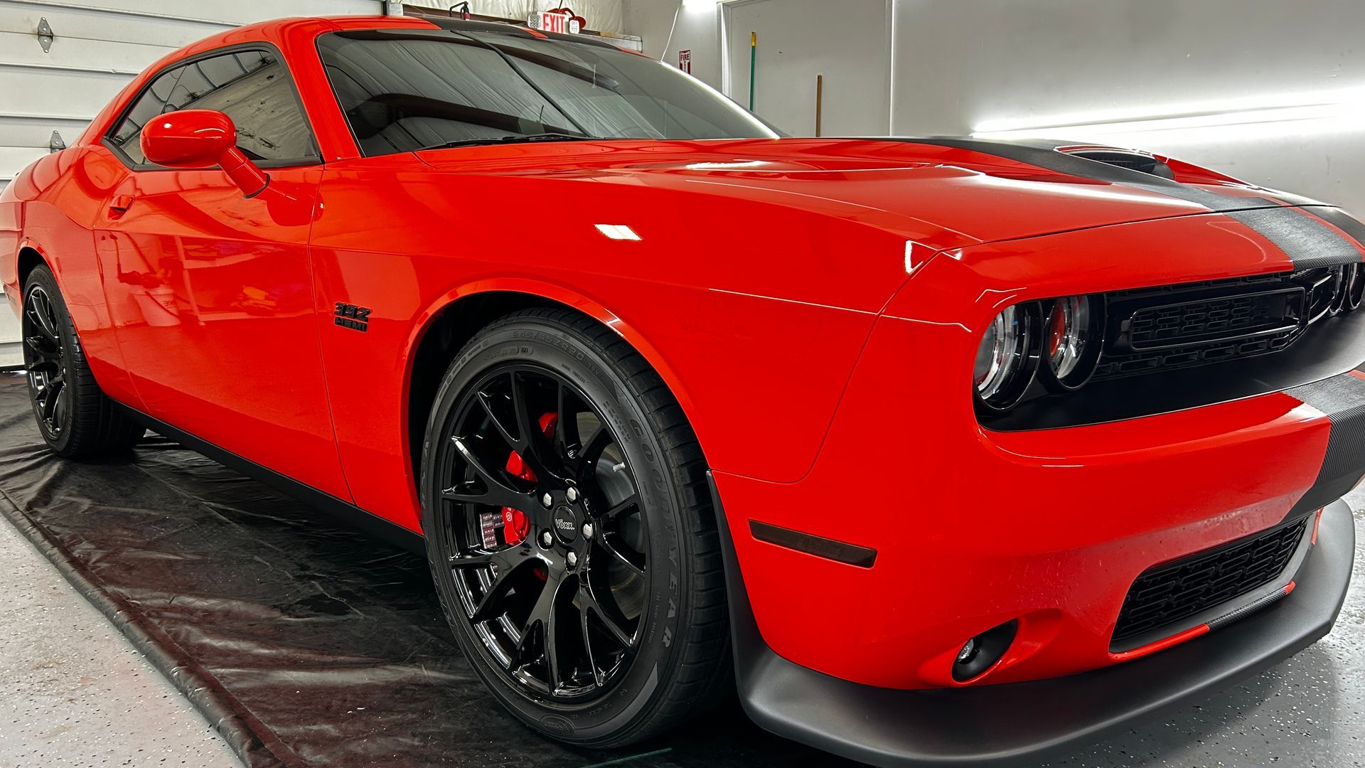 Red sports car with black wheels parked indoors on a showroom floor