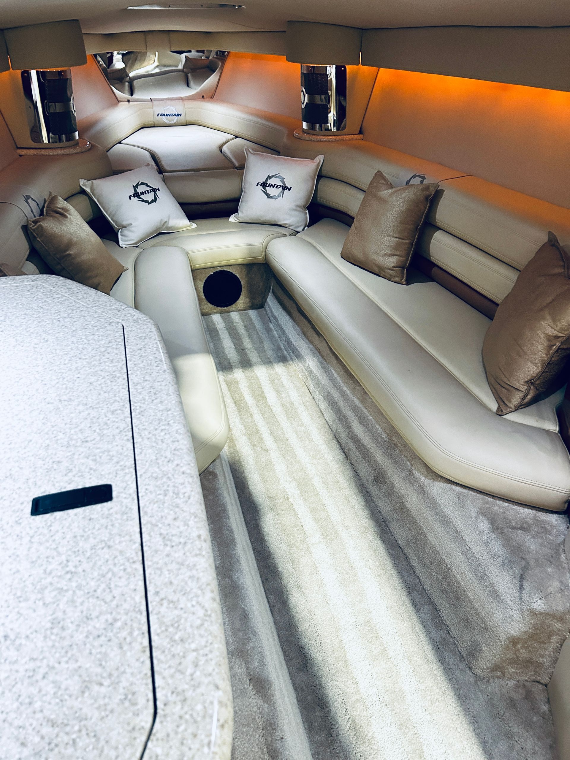 Luxury yacht cabin with cream leather seating, beige pillows, and warm orange accent lighting