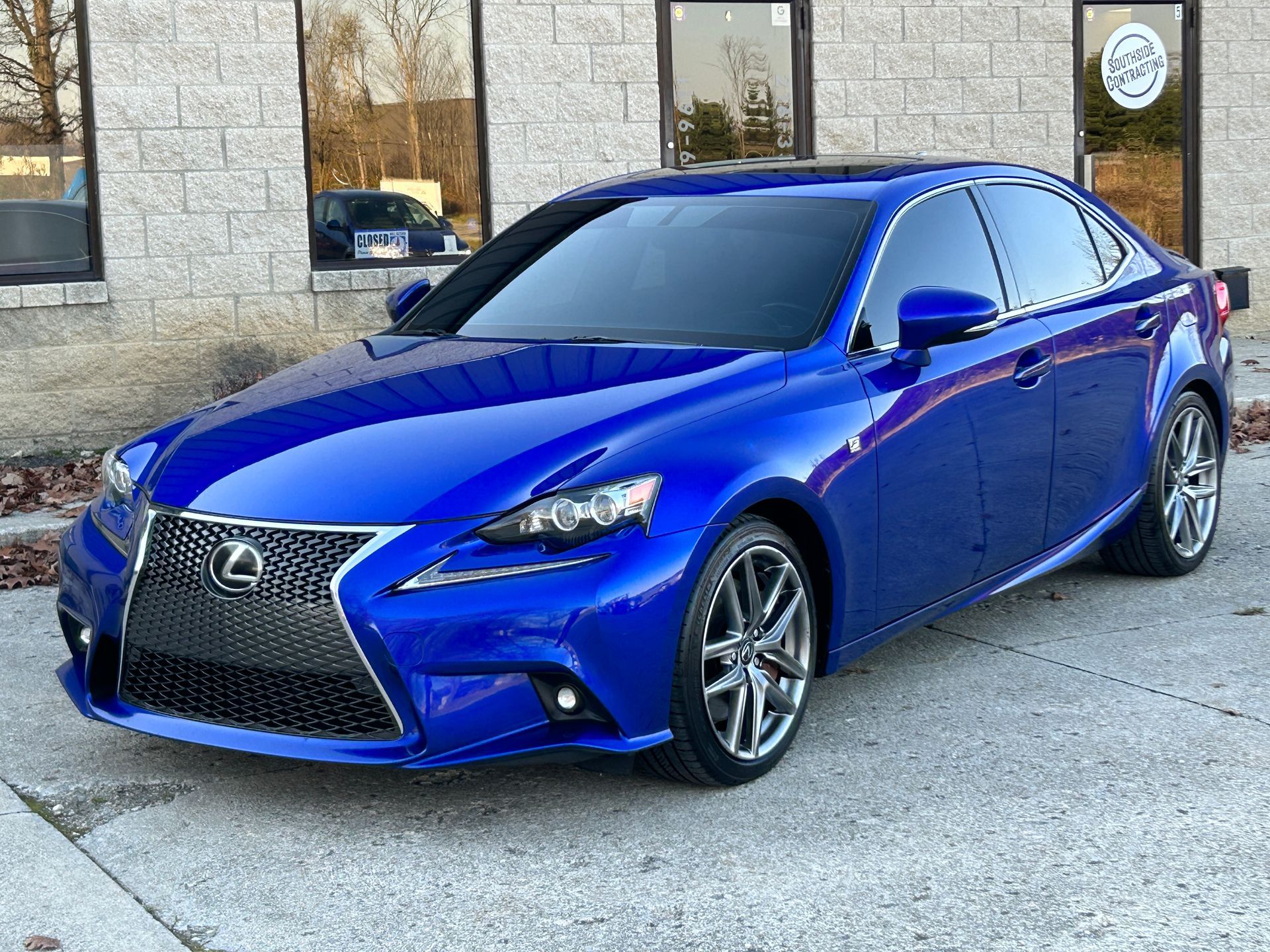 Blue Lexus sedan parked outside a building with stone walls and windows