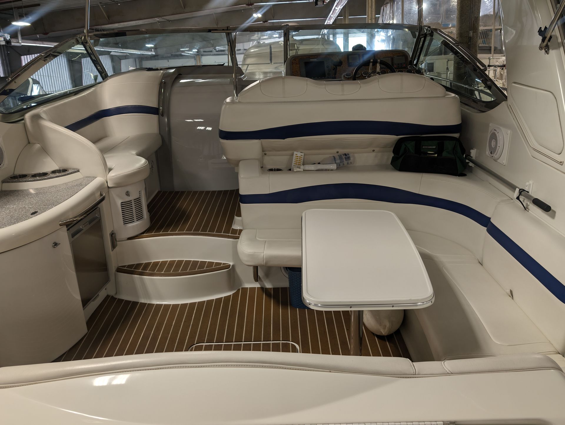 Interior of a white-and-blue boat cabin with cushioned seating and wood-pattern flooring