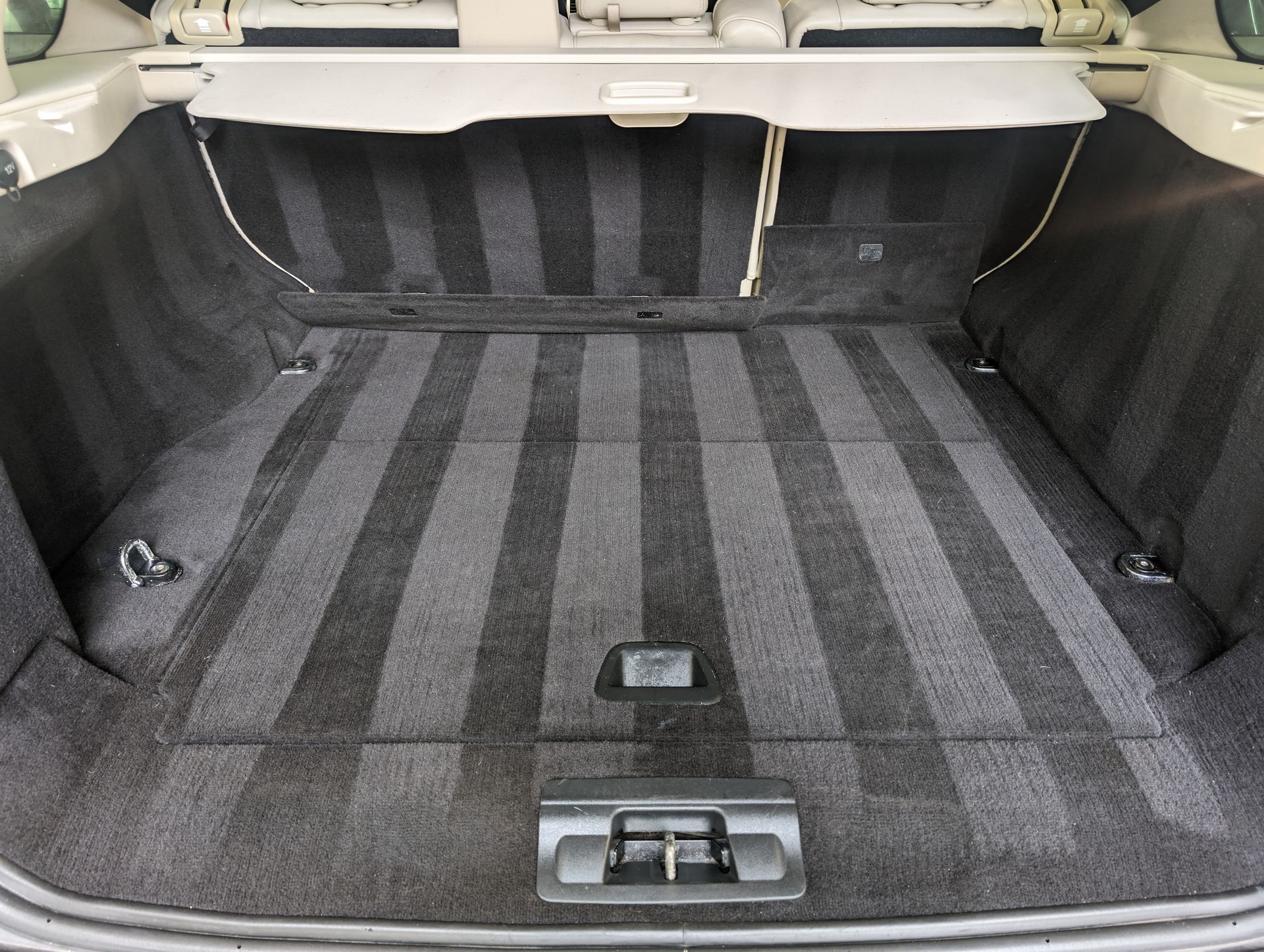 Open car trunk with gray-and-black carpeted cargo area and rear seatback visible.