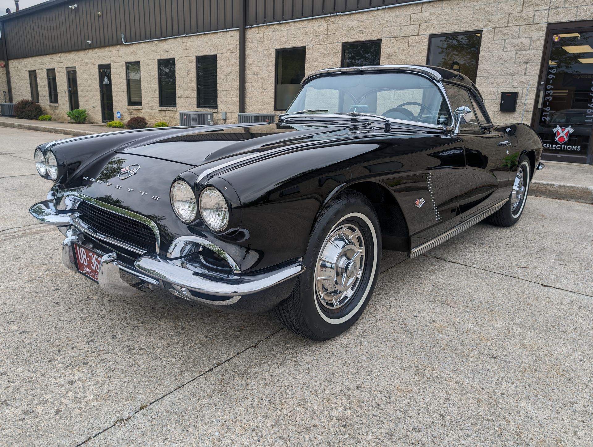 Black classic Corvette convertible parked outside a stone building